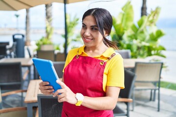 Poster - Young beautiful arab woman waitress smiling confident using touchpad at coffee shop terrace