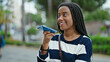 © Krakenimages.com - African american woman sending voice message with smartphone at park