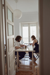 Wall Mural - Married couple freelancers sit at table in living room with laptops and working from home office