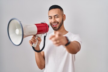 Sticker - Young hispanic man shouting through megaphone smiling happy pointing with hand and finger