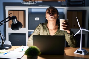 Canvas Print - African woman working using computer laptop at night looking at the camera blowing a kiss on air being lovely and sexy. love expression.