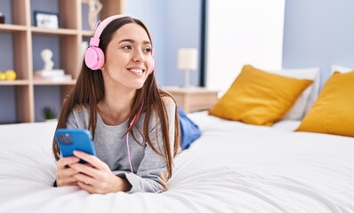Canvas Print - Young beautiful hispanic woman listening to music lying on bed at bedroom