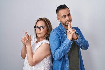 Wall Mural - Hispanic mother and son standing together holding symbolic gun with hand gesture, playing killing shooting weapons, angry face