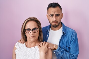 Sticker - Hispanic mother and son standing together skeptic and nervous, frowning upset because of problem. negative person.