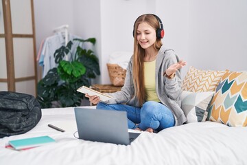 Canvas Print - Young caucasian woman studying with laptop sitting on the bed celebrating achievement with happy smile and winner expression with raised hand