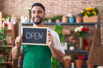 Sticker - Hispanic young man working at florist holding open sign smiling and laughing hard out loud because funny crazy joke.