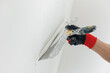 © Parilov - Closeup hands man drywall worker using trowel for plasterer putting stucco on plasterboard white wall