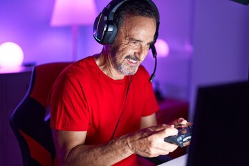 Canvas Print - Middle age man streamer playing video game using joystick at gaming room