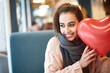 Happy smiling woman with balloon in the form of heart in a cafe. Couple in love on a date. Love story and Valentines Day concept