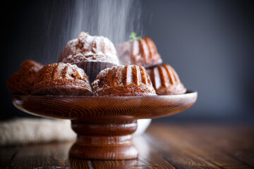 sweet honey muffins in powdered sugar on a wooden table