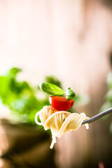 Wall Mural - Italian cuisine. Pasta on fork. Pasta with olive oil, garlic, basil and tomatoes. Spaghetti with tomatoes