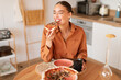 Pizza perfection. Satisfied woman delighting in her kitchen creation, enjoying homemade meal and biting slice