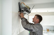 © DimaBerlin - Man technician worker in uniform fixing repairing apartment air conditioner, installing wall-mounted mini split. AC unit maintenance concept
