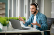 © Prostock-studio - Video Call. Cheerful Young Businessman In Headphones Making Teleconference In Office