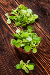 Canvas Print - Fresh lamb's lettuce salad in wooden bowl on old wooden vintage background. Fresh salad, rustic vintage country style image.