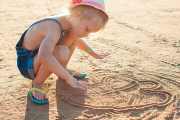 Poster - Cute little girl playing with sand on the beach. Active summer vacation.