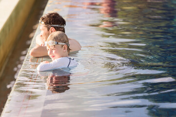 Poster - family of two, father and son enjoying together at infinity pool at resort