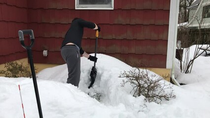 Wall Mural - young man shoveling the snow on the back hurricane door after the snow storm in February