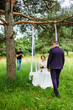 Videographer shoots a film with the newlyweds on a rope swing in a pine forest