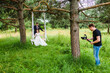 Videographer shoots a film with the newlyweds on a rope swing in a pine forest