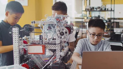 Group of multinational schoolchildren working on laptop, studying and programming at robotics engineering class. School classroom of futuristic technologies