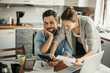 © Geber86 - Young couple going over their bills at home in the kitchen