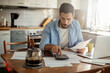 © Geber86 - Young man going over his home finances in the kitchen