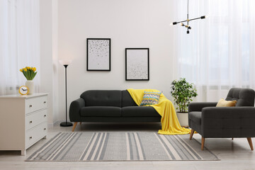 Wall Mural - Spring atmosphere. Stylish living room interior with comfortable furniture and bouquet of beautiful yellow tulips