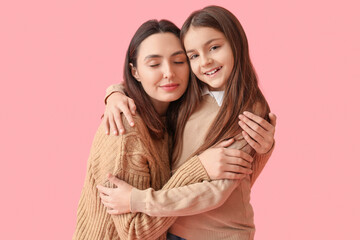Wall Mural - Little girl and her mother in knitted sweaters hugging on pink background