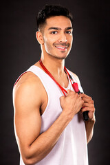 Wall Mural - young fit indian man wearing workout outfit on dark background