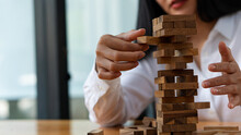 Young Woman Placing Wooden Blocks On Tower, Business Plan And Strategy, Risk Concept To Grow Business With Jengka Wooden Blocks