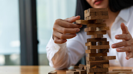 Young woman placing wooden blocks on tower, business plan and strategy, risk concept to grow business with jengka wooden blocks