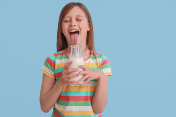 Poster - Funny little girl with bottle of milk on light blue background