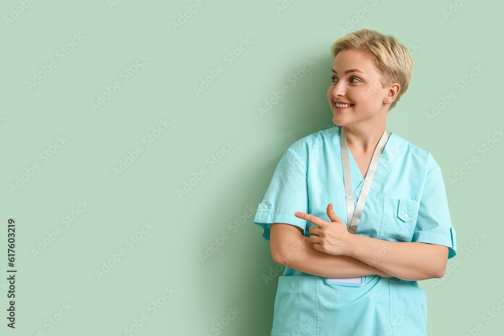 Female medical intern pointing at something on green background