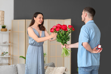 Wall Mural - Young man with flowers proposing to his girlfriend at home