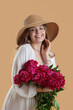 © Pixel-Shot - Beautiful young woman with bouquet of peony flowers on beige background