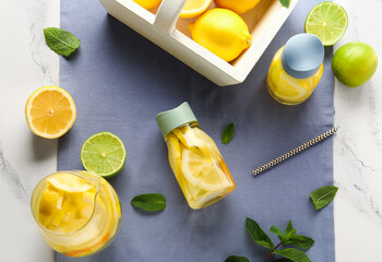 Bottles and jug of infused water with lemon on white marble background