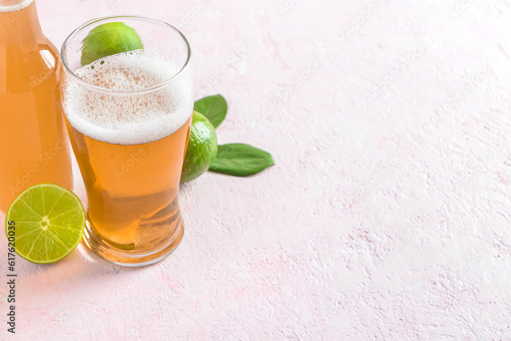 Glass and bottle of cold beer with lime on light background