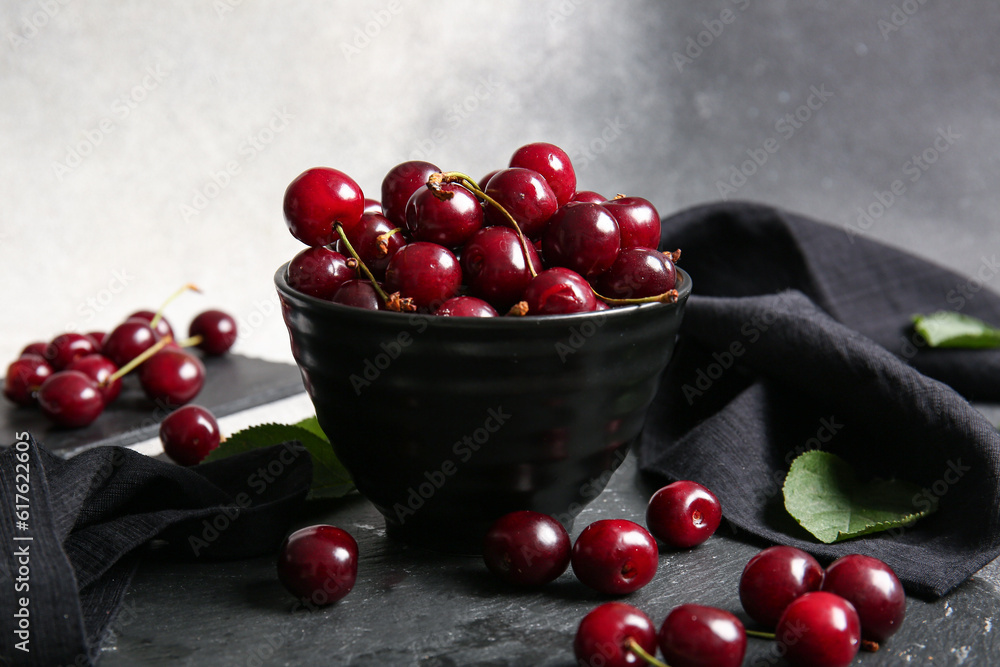 Board with bowl of sweet cherries on table, closeup
