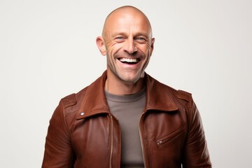 Portrait of a laughing bald man in a brown leather jacket on a white background