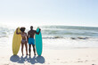 © wavebreak3 - Rear view of african american couple with surfboards standing on sunny beach facing sea, copy space