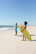 © wavebreak3 - African american man and woman with surfboards standing on sunny beach looking to sea, copy space