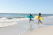 © wavebreak3 - African american couple carrying surfboards running on sunny beach to the sea, copy space