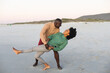 © wavebreak3 - Happy african american couple dancing and smiling on beach at sundown