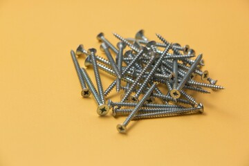 Wall Mural - Closeup of a bunch of screws and bolts on a yellow background