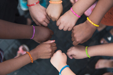 multiethnic children hands together with rainbow bracelets. friendship on a elementary age students 