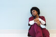 Tired african american female doctor sitting on floor in corridor at hospital, copy space