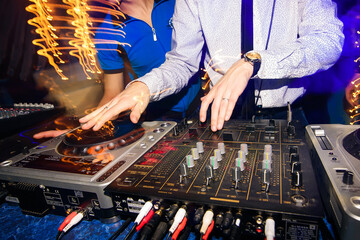 Wall Mural - DJ hands mix music on professional mixer in booth at a party in nightclub