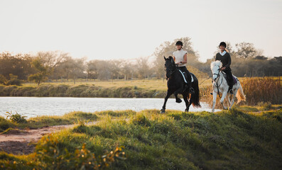 Wall Mural - Horse riding, freedom and equestrian with friends in nature on horseback by the lake during a summer morning. Countryside, hobby and female riders outdoor together for travel, fun or adventure