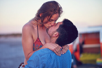 Kiss, love and couple at the beach on date, vacation or road trip in summer at sunset, together and romantic adventure. People, dating and support in relationship, happiness or boyfriend and girl